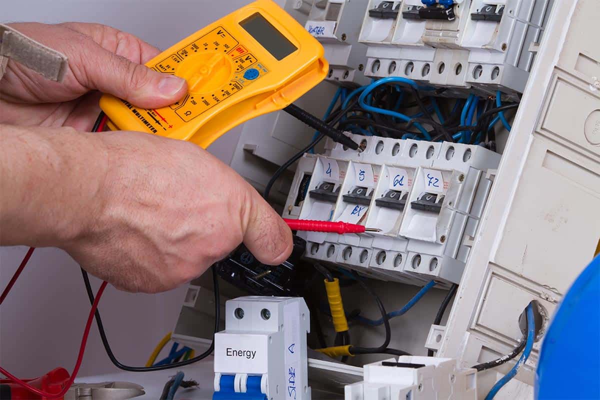 Elektryk w Giedlarowej sprawdza połączenia elektryczne w rozdzielnicy za pomocą multimetru cyfrowego.