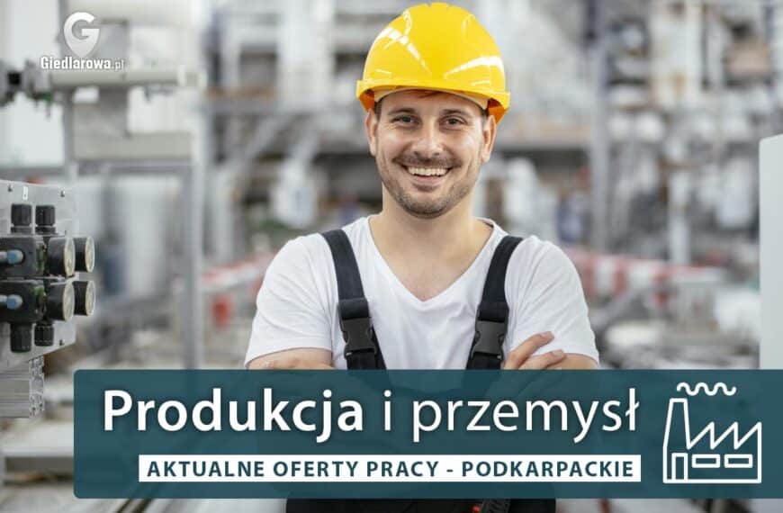 Uśmiechnięty pracownik w zakładzie przemysłowym, w kasku i odzieży roboczej.