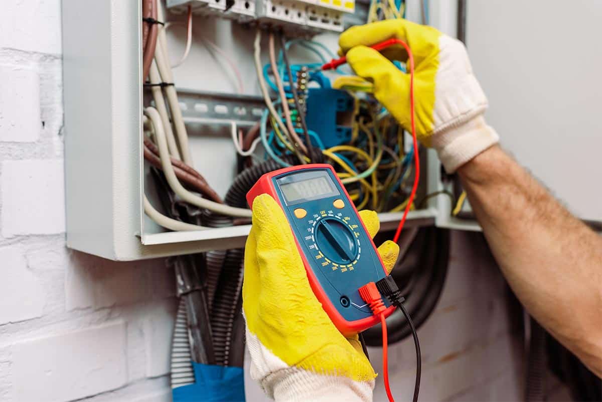 Elektryk w Giedlarowej testuje instalację elektryczną miernikiem cyfrowym w rozdzielni elektrycznej