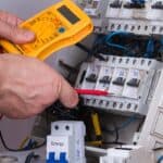 Elektryk w Giedlarowej sprawdza połączenia elektryczne w rozdzielnicy za pomocą multimetru cyfrowego.