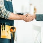 Dwóch ludzi w pomieszczeniu podaje sobie ręce po ustaleniu Hydraulik usługi sanitarne w Giedlarowej.