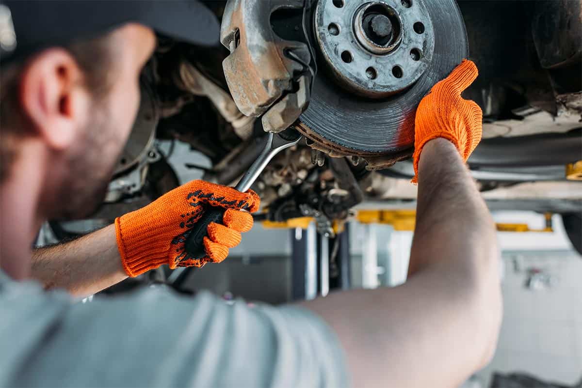 Mechanik samochodowy w Giedlarowej naprawia układ hamulcowy auta w warsztacie.