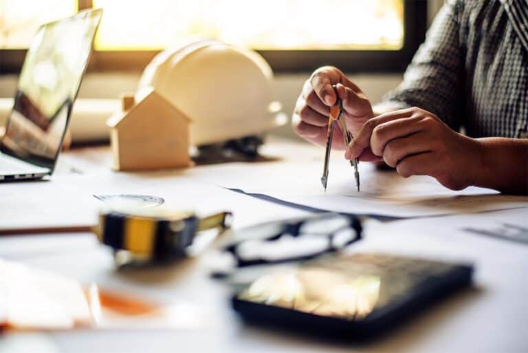 Architekt przy biurku projektuje model domu - usługi projektowe Giedlarowa.