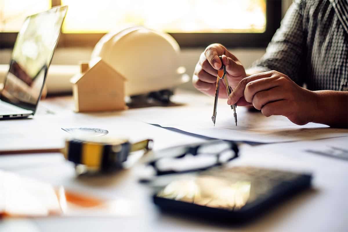 Architekt przy biurku projektuje model domu - usługi projektowe Giedlarowa.